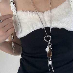 Detail of a vintage amber teardrop and heart fringe pendant on a silver sweater chain