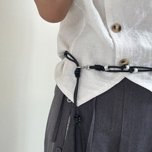 Close-up of black braided cord waist belt with silver buckle on minimalist outfit