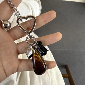 Detail of water drop resin pendant with heart carabiner and black tassel keychain