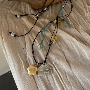 Close-up of handmade woven cord necklace with yellow star pendant and silver charms