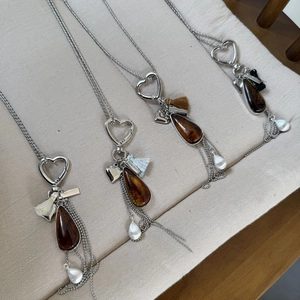 Macro detail of teardrop resin pendants with heart clasps and colorful silk tassels