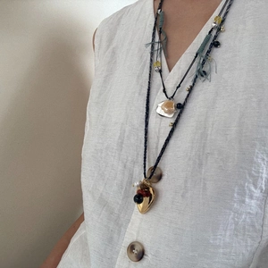 Macro detail of layered boho necklaces with gold heart pendant and natural stone accents
