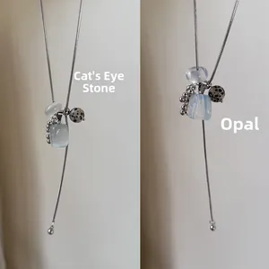 Detail view of cat's eye and opal stone pendants on thin snake chain necklaces