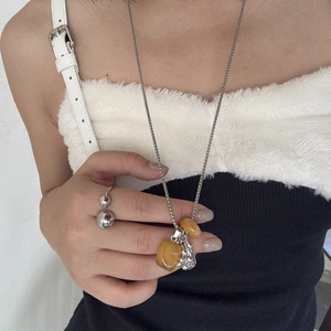 Close-up of titanium steel necklace and double-ball ring on black and white outfit