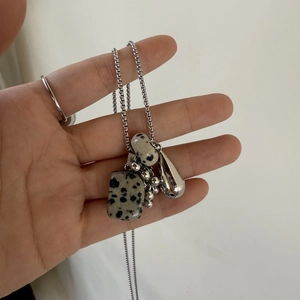 Detailed view of the natural stone pendant and polished metal drops on a fine chain