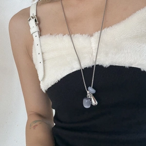 Detail of long titanium steel necklace featuring light blue stones and a silver teardrop pendant