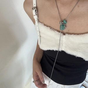 Detailed close-up of a long natural stone necklace with green beads on a white vest model
