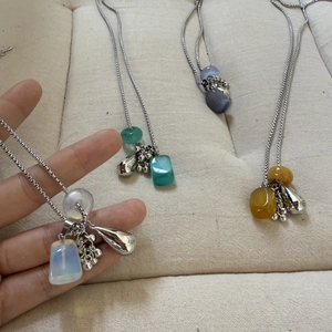 Detail of beaded gemstone necklaces in moonstone white, green, purple and amber tones