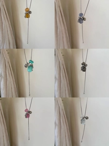 Detail view of colorful natural stone bead clusters on long titanium steel Y-necklaces