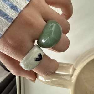 Vue macro de larges bagues en résine marbrée verte avec motif cœur noir au doigt