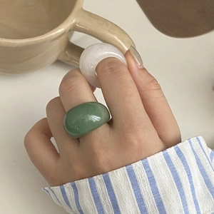Détail de larges bagues en jade translucide vert pâle et blanc sur la main d'un mannequin