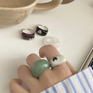 Gros plan de bagues larges en résine de couleurs variées avec détails cœur en métal