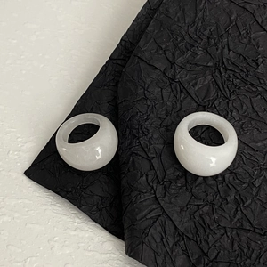 Détail de deux bagues larges blanches translucides au fini brillant sur papier texturé