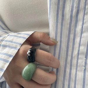 Détail d'une large bague en résine et d'un anneau à motif cœur portés avec style