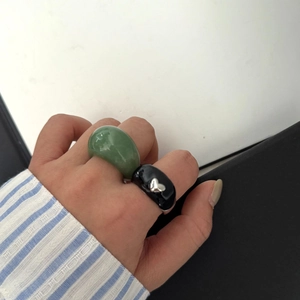 Vue rapprochée d'une bague en résine verte et bague noire avec cœur argenté