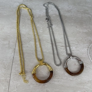 Detail of amber tortoiseshell circle pendants on gold and silver stainless steel chains