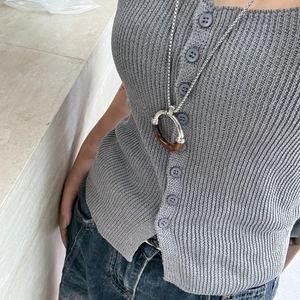 Minimalist stainless steel necklace with amber resin circle pendant on grey knitwear