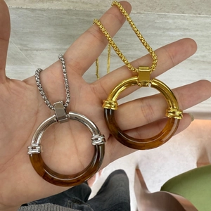 Detail view of chunky resin hoop pendants on thick chain necklaces in gold and silver