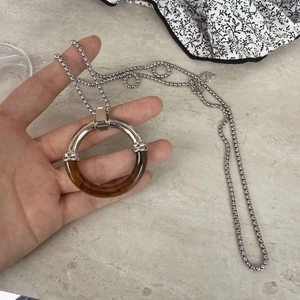 Detail of minimalist stainless steel necklace with amber resin and silver ring pendant