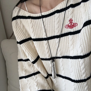 Ciondolo a rotolo in metallo vintage su cordoncino nero indossato con maglione