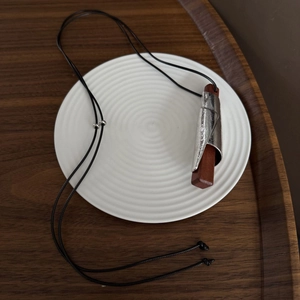 Dettaglio della collana con cordino nero regolabile e pendente in legno e argento