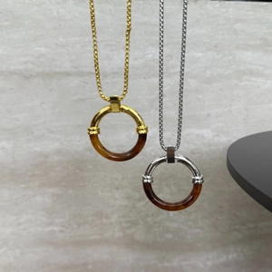 Detail of round amber resin and stainless steel pendants in gold and silver finish