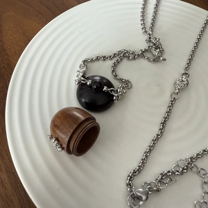 Dettaglio della collana con ciondolo in legno vintage su piatto in ceramica bianca