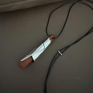 Dettaglio del ciondolo in metallo argento con anima in legno su cordoncino regolabile