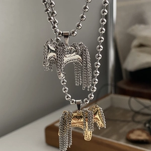 Dettaglio dei ciondoli a forma di cavallo con nappe metalliche su collane a sfere