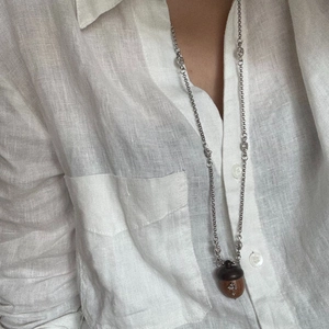Dettaglio del ciondolo a ghianda con trama in legno e diamante a stella su collana