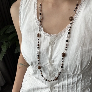 Detalle de un collar largo artesanal con piedras naturales y perlas de estilo boho