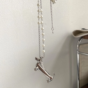 Detail of silver dachshund pendant with elegant pearl and metal chain necklace
