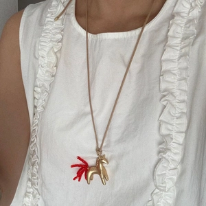 Collana con ciondolo a forma di pony dorato e nappe di perline rosse su cordino intrecciato