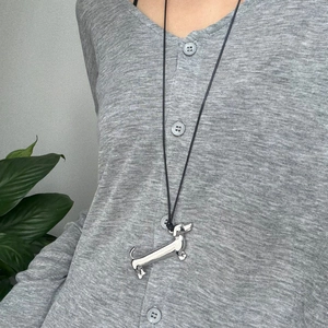 Close-up of a cute silver dachshund dog pendant worn on a black cord necklace