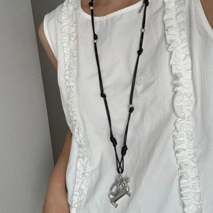 Silver dachshund puppy pendant on a black cord necklace worn with a white ruffle top