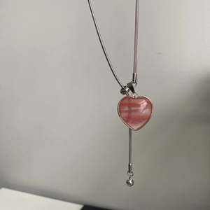 Nahaufnahme des rosa Herzanhängers mit silberner Schlangenkette und Tigeraugen-Struktur