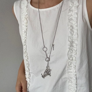 Macro detail of a silver dachshund pendant necklace worn on a white ruffled top