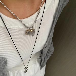 Dettaglio di una collana a strati con nappa metallica e pendente geometrico