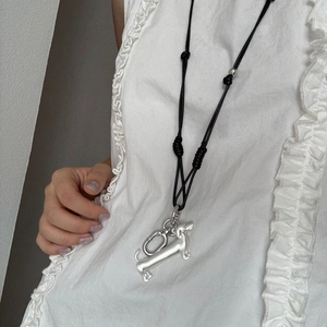 Detail of silver dachshund pendant on adjustable black cord necklace over white blouse