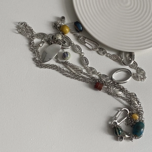 Detalle de collar largo vintage con cuentas de piedra de colores y dijes metálicos variados