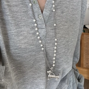 Detail of dachshund dog pendant on silver and pearl bead long necklace worn by a model