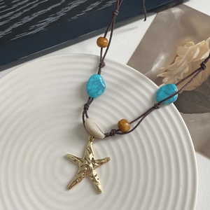 Detalle del colgante de estrella de mar con cuentas turquesas en un collar de cordón trenzado
