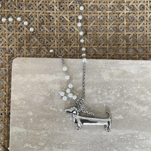 Macro shot of silver dachshund pendant on a mixed metal chain with imitation pearls