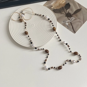 Detalle de un collar con cuentas de mármol y perlas sobre una bandeja de cerámica