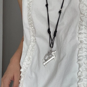 Detailed close-up of a silver dachshund dog pendant hanging on a minimalist black rope cord