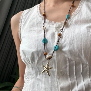 Primer plano del collar bohemio de estrella de mar con cuentas turquesas y caracola