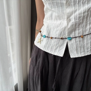 Detalle de la cadena bohemia para la cintura con cuentas turquesas y dije de estrella
