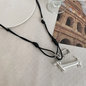 Close-up of silver dachshund pendant on black woven cord with adjustable clasp detail