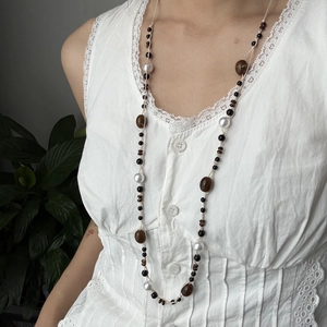 Detalle de collar de cuentas con resina ámbar y perlas blancas en top de encaje blanco