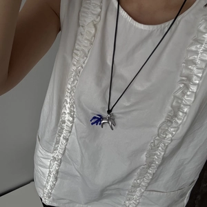 Primo piano di una collana con ciondolo a cavallo d'argento e perline blu su camicia